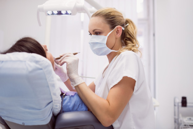 dentist-examining-female-patient_107420-65395